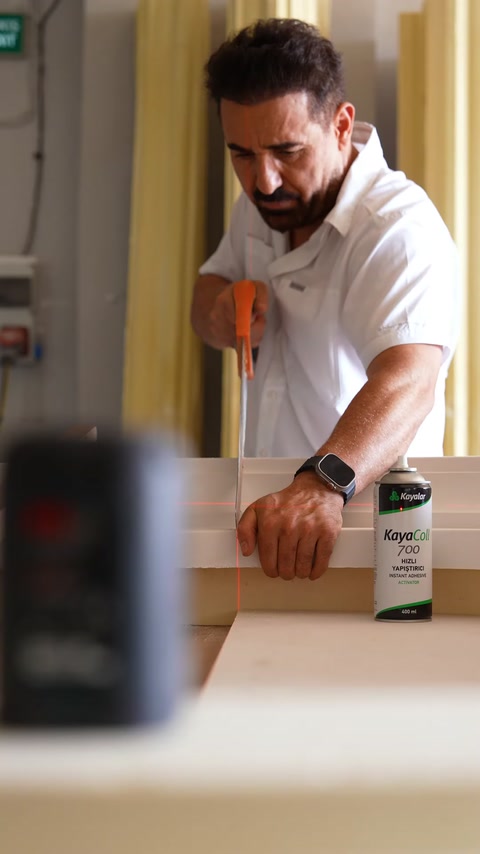 A craftsman carefully cuts a decorative profile component with the help of a ruler.