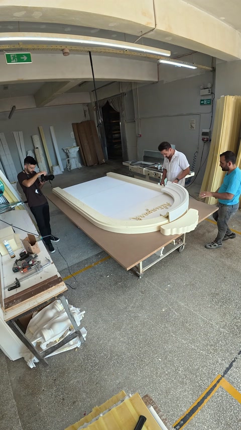 The workshop team works together on a large curved decorative frame.