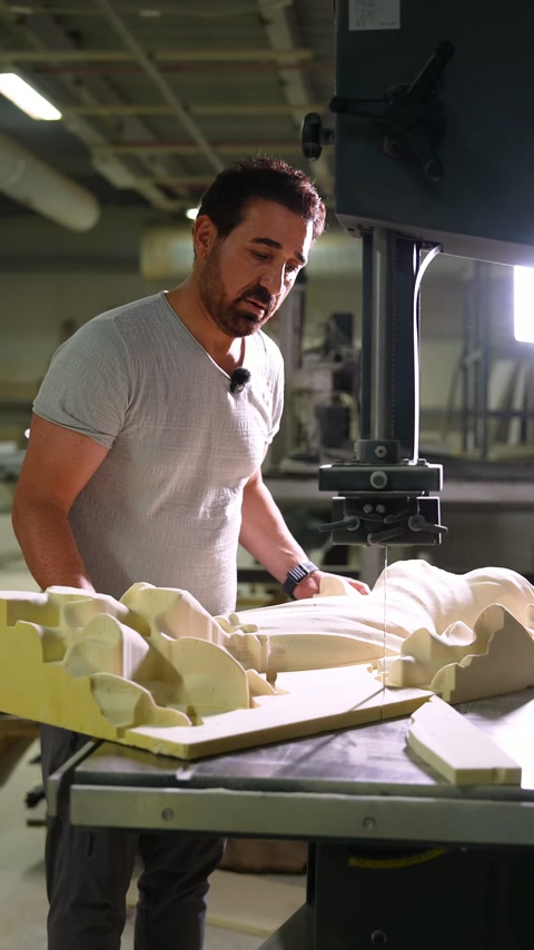 Specialist inspects carved decorative pieces at production workstation.
