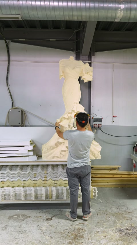Specialist examines large ornamental relief in vertical position at workshop.