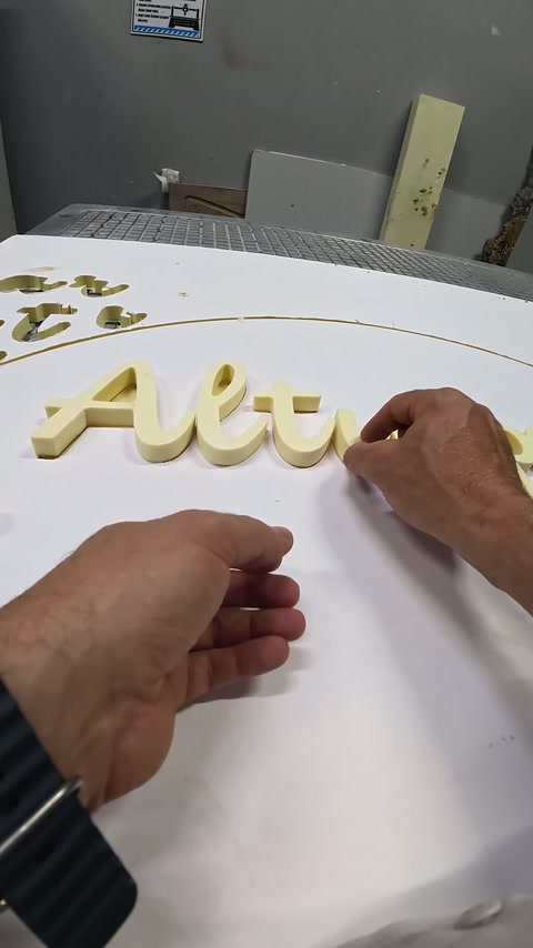 Embossed text pieces are aligned and positioned by hand on white panel.