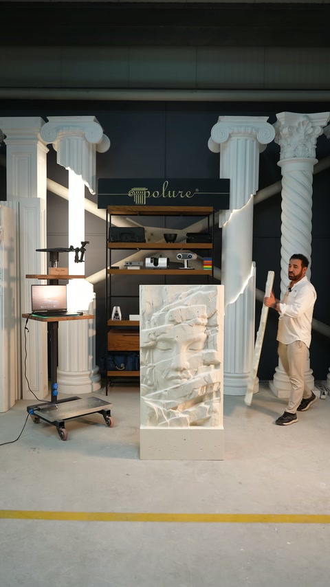 Presenter lifts a long piece to be added to the relief composition from the floor.