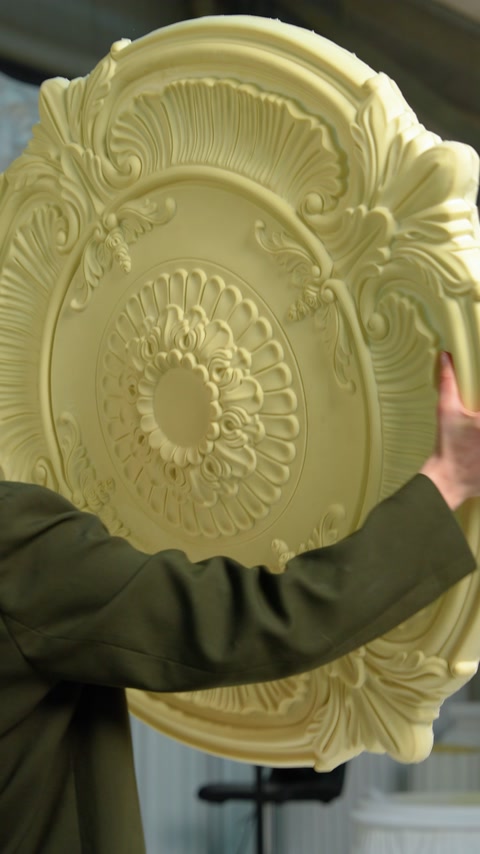 Operaio che tiene un medaglione da soffitto giallo non verniciato prima della finitura