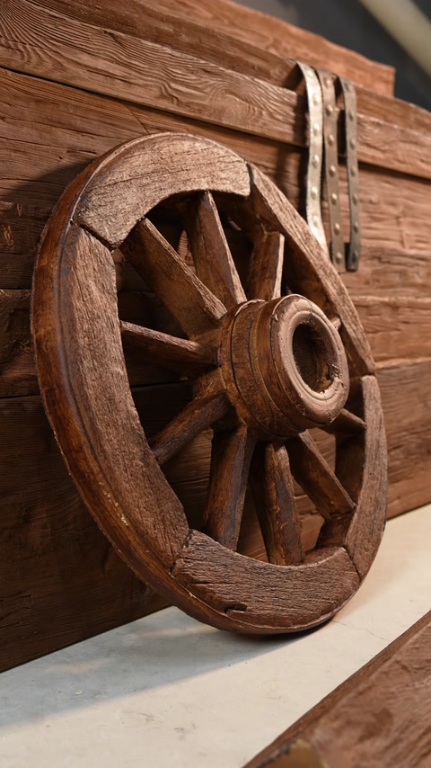 Ruota di carro in legno accanto a una trave rustica effetto legno