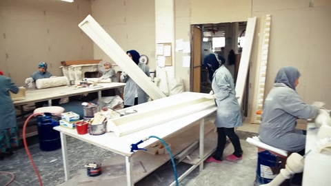 Artigiano che solleva un lungo profilo in poliuretano sul tavolo da lavoro