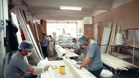 İki çalışan uzun söve parçalarını geniş çalışma masasında düzenliyor.