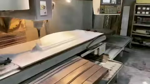A large polyurethane sheet advances into a cutting machine for shaping.