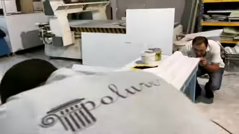 A worker finishes the edges and motif details of a polyurethane decorative element.