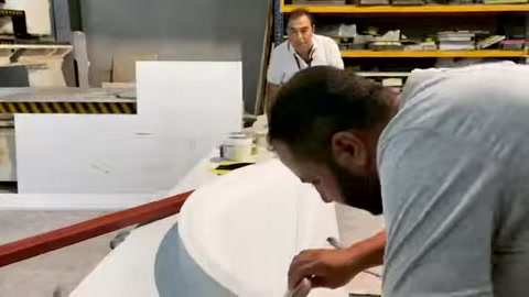 A craftsman manually refines the joining surface of a curved exterior facade surround.