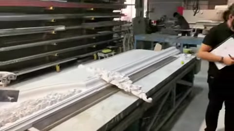 Elementi lunghi per cornici e motivi decorativi vengono disposti sul banco di produzione