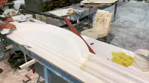 Un elemento modello curvo lavorato viene levigato a mano sul tavolo di produzione