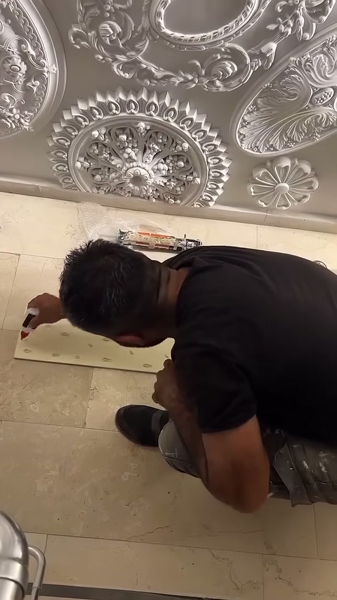 Montaj ustası açık renkli panel arkasındaki yapıştırıcı uygulamasını sürdürüyor.