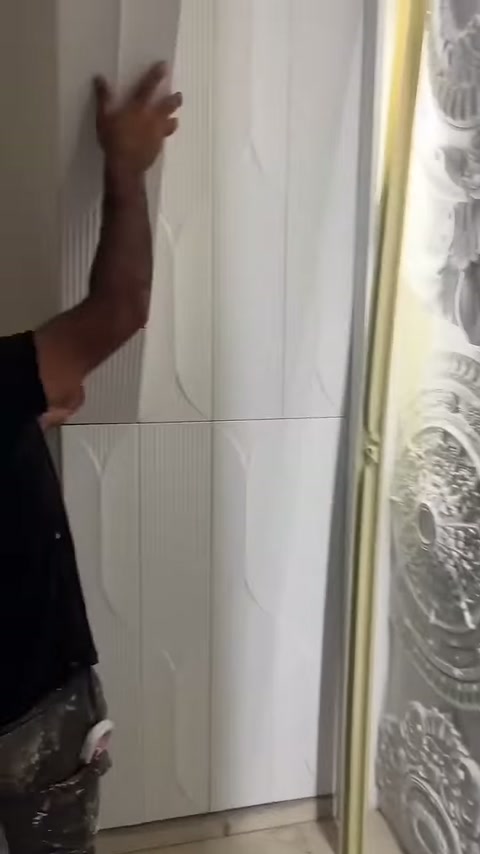 Usta beyaz çizgili paneli duvardaki dikey boşluğa yerleştiriyor.
