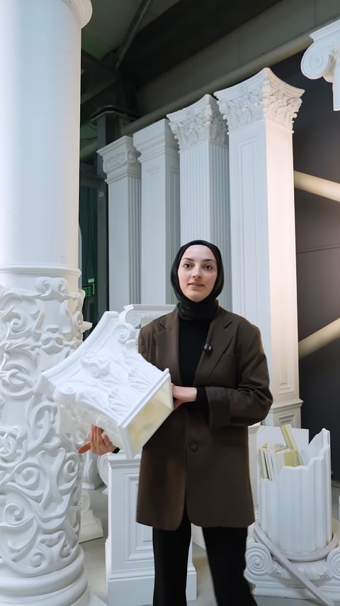 The presenter holds an ornate polyurethane column capital in front of the columns