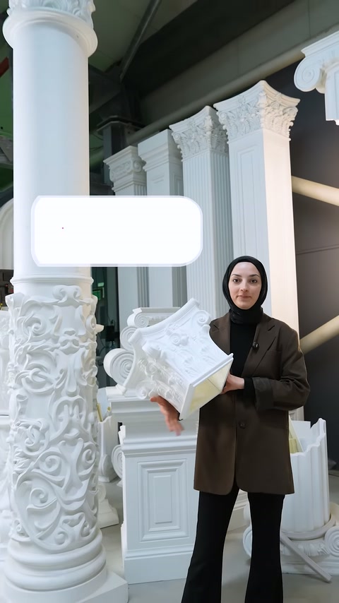 Presenter holds a decorated white column capital sample while speaking