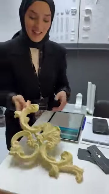Kıvrımlı poliüretan süs, stant görevlisi tarafından masadan alınıyor