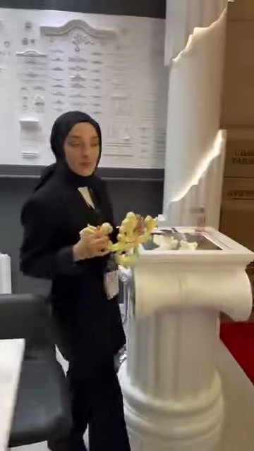 Kabartmalı flex süsleme, sütun ve kutular önünde elde gösteriliyor