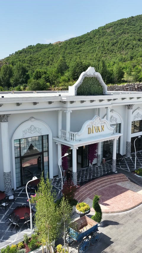 Dağ manzarası önündeki sütunlu ve kemerli düğün salonu cephesi