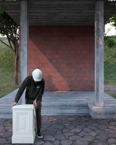 Un operaio trasporta la base del piedistallo in poliuretano verso il sito di installazione della pergola esterna.