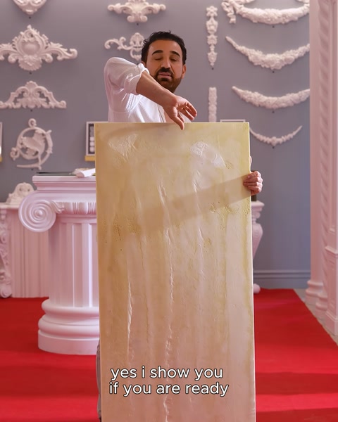 Manufacturer holding white-primed relief panel in hand