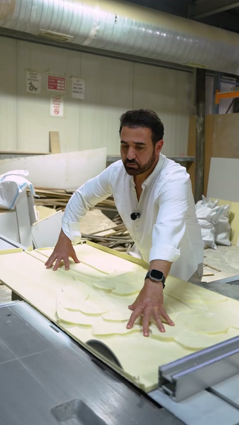 Il pannello in rilievo viene guidato con attenzione a due mani sul tornio CNC.