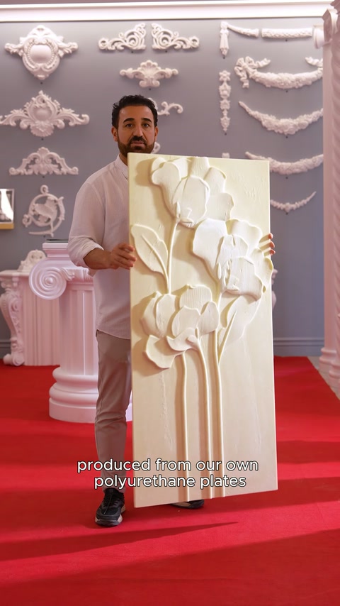 Il pannello a rilievo floreale con steli di fiori viene tenuto di fronte nella sala espositiva.