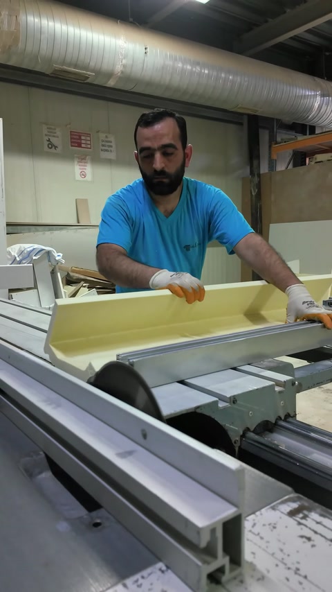 Worker cuts a straight polyurethane fireplace component on a table saw.