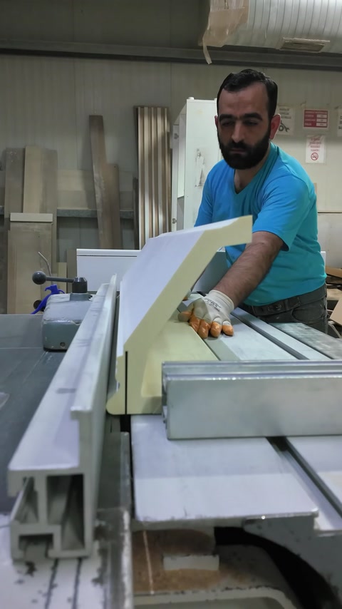 Craftsman guides an angled mantel piece through precision cutting equipment.