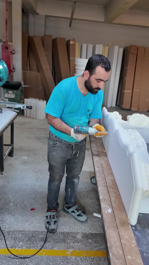 Craftsman refines the ornate mantel crest with a handheld tool.