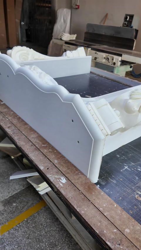 Partially assembled white fireplace surround displayed across the workbench.