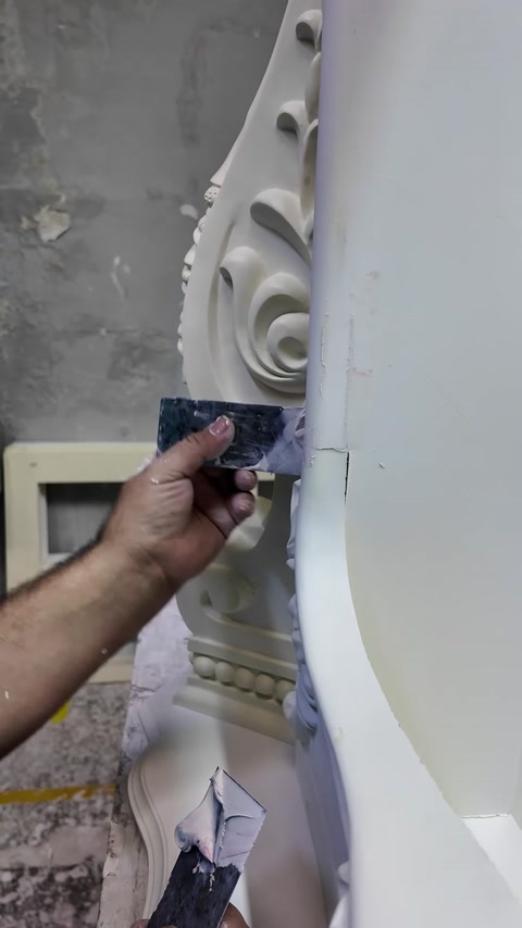 Craftsman smooths a seam beside the fireplace scroll ornament.