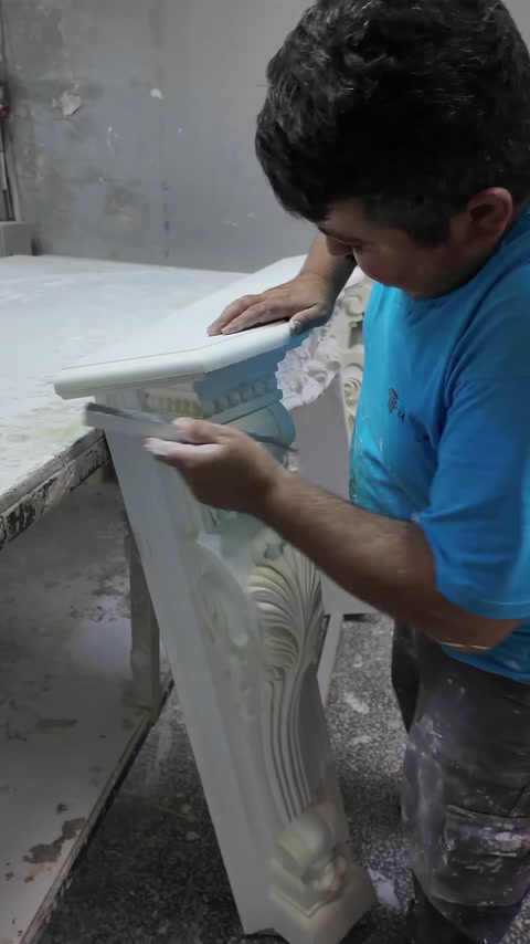 Worker hand-sands the projecting mantel shelf for a smooth edge.