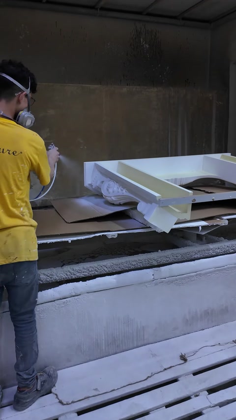 Fireplace surround components receive a sprayed finish inside the booth.