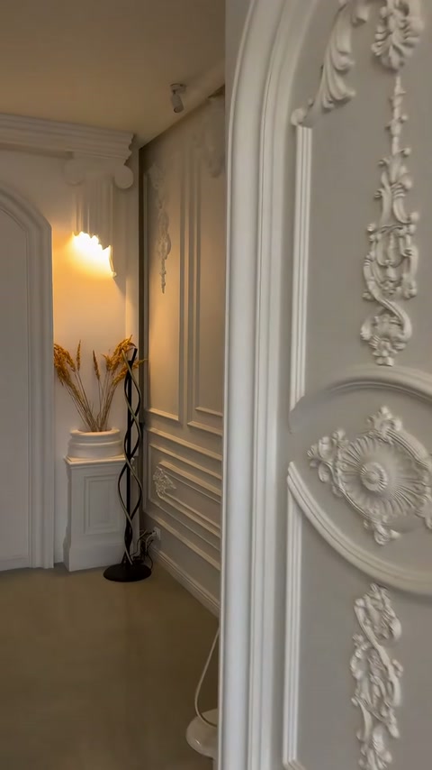 Cornice porta con motivo floreale in rilievo esposta accanto a una parete con listelli