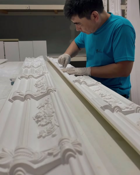 Un operaio con i guanti leviga a mano un lungo profilo per cornice