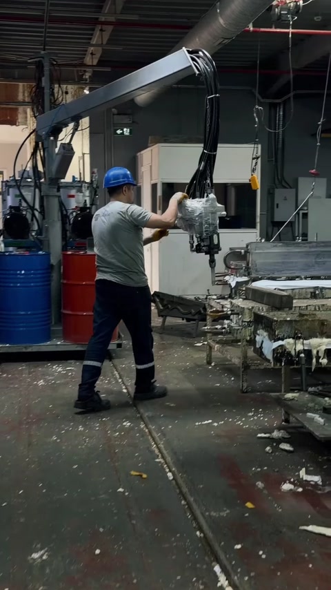 Un operaio utilizza l'attrezzatura per la colata accanto ai fusti delle materie prime