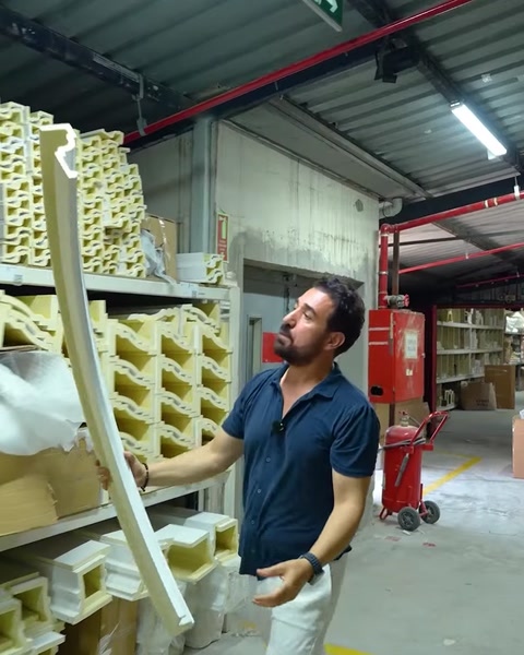 Operaio che tiene una striscia di cornice flessibile curva nel corridoio della fabbrica