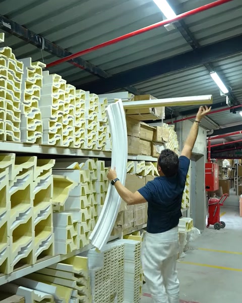 Uomo che solleva una cornice flessibile arrotolata dall'unità di scaffali del magazzino