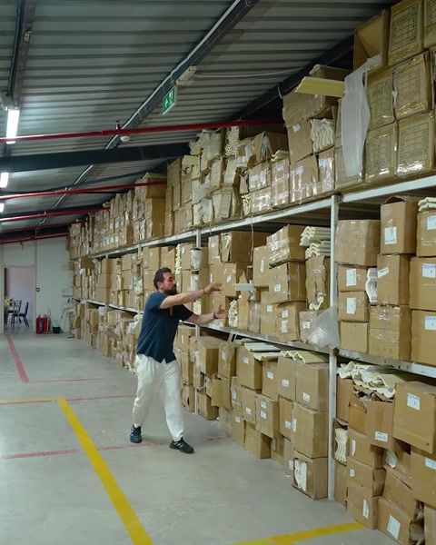 Uomo che cammina nel corridoio del magazzino portando una lunga striscia di cornice dritta