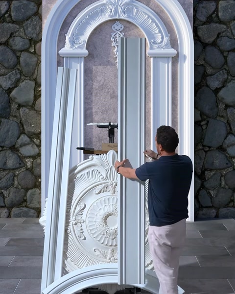 Operaio che adatta una colonna in gesso nel design della parete decorativa ad arco