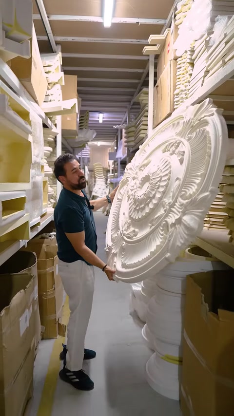 Man holding large circular ceiling medallion in factory warehouse