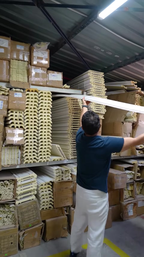 Worker pulling long flexible cornice molding from storage rack