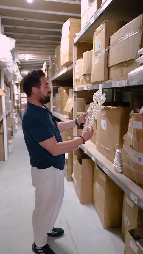Worker reaching for ornate decorative applique on warehouse shelf
