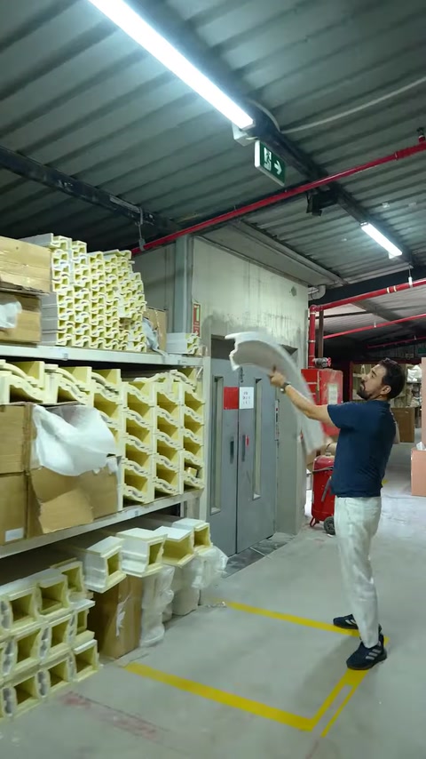 Man bending flexible polyurethane molding beside coiled profile stock