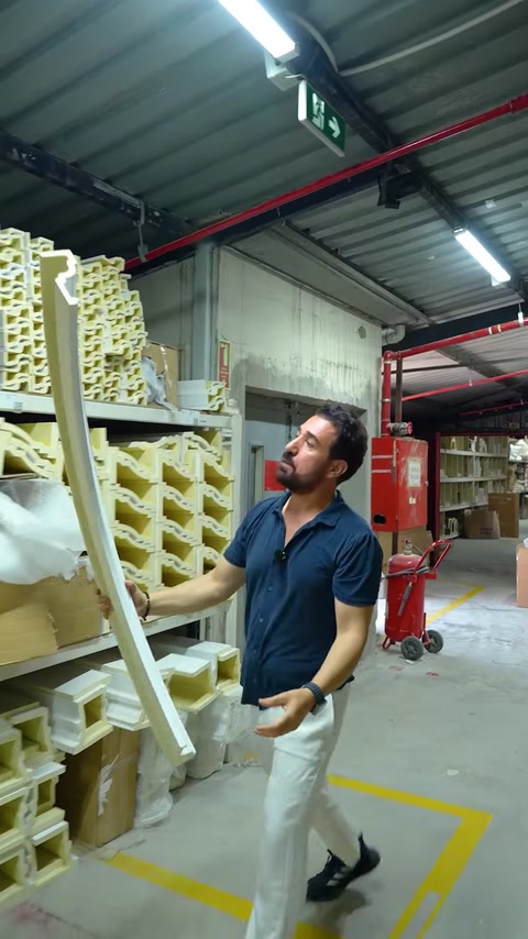 Worker holding curved flex molding strip in factory aisle