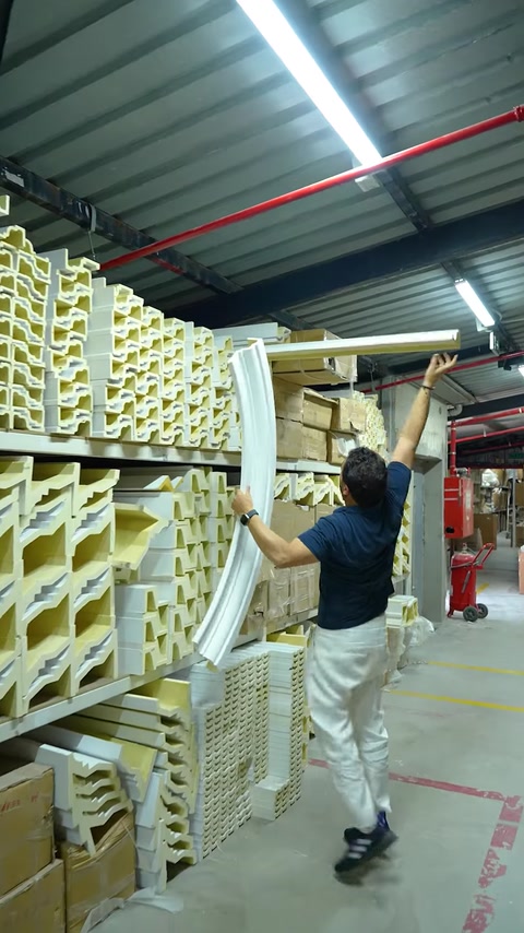 Man lifting coiled flexible molding from warehouse shelving unit