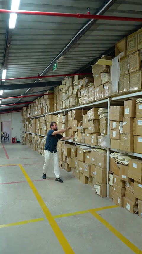 Man walking warehouse aisle carrying long straight molding strip