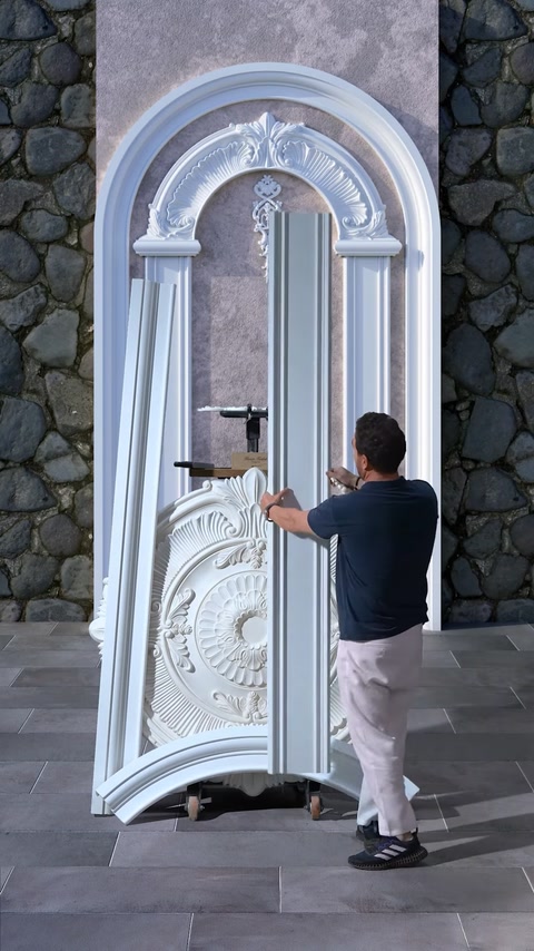 Worker fitting plaster column into arched decorative wall design