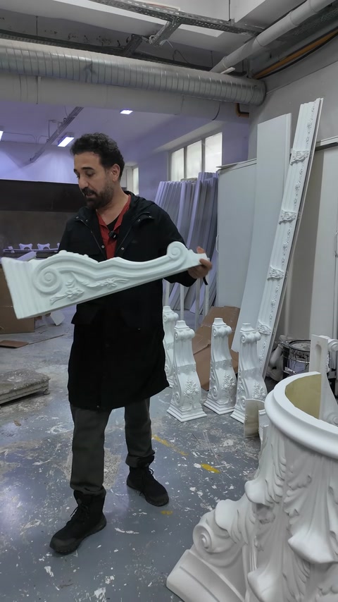 A white decorative profile with curved ornaments is displayed in the workshop