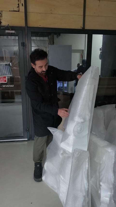 An ornamental column capital is carefully removed from its protective packaging